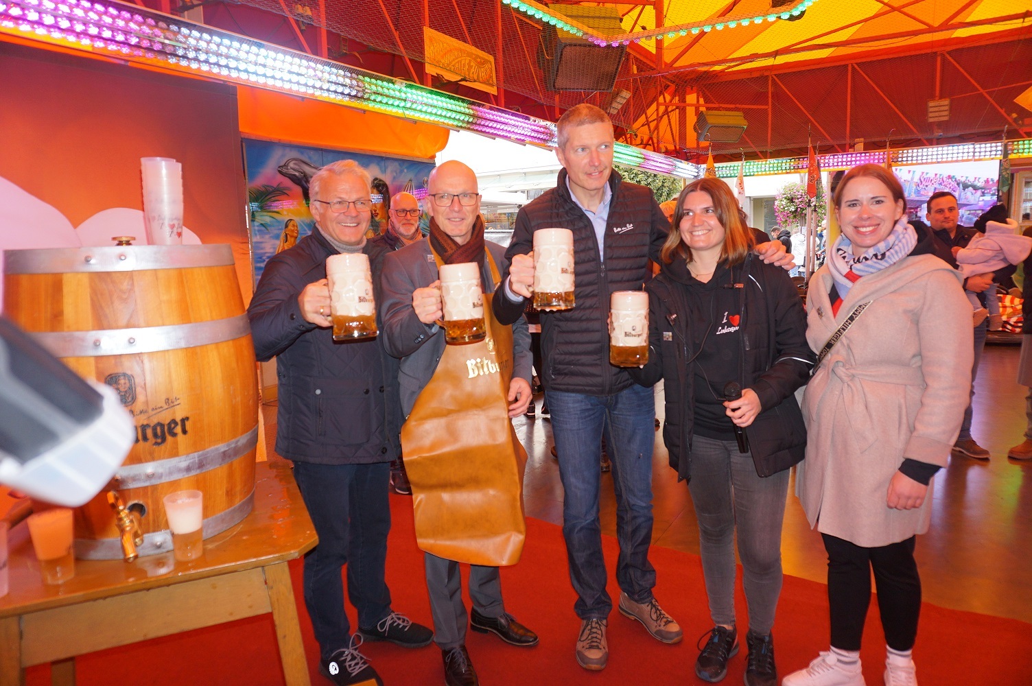 Fünf Personen stehen auf der Fläche des Autoscooters und haben Bierkrüge in der Hand.