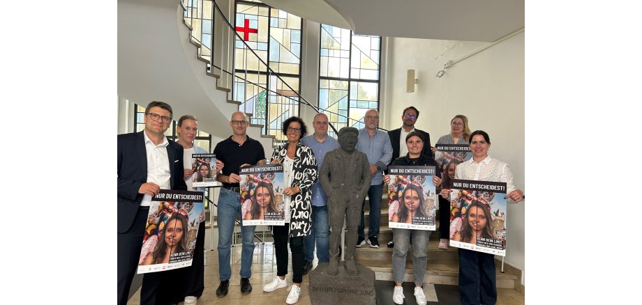 Viele Menschen stehen gemeinsam auf den Treppen des Rathauses und halten das Plakat zum Jugendschutz hoch