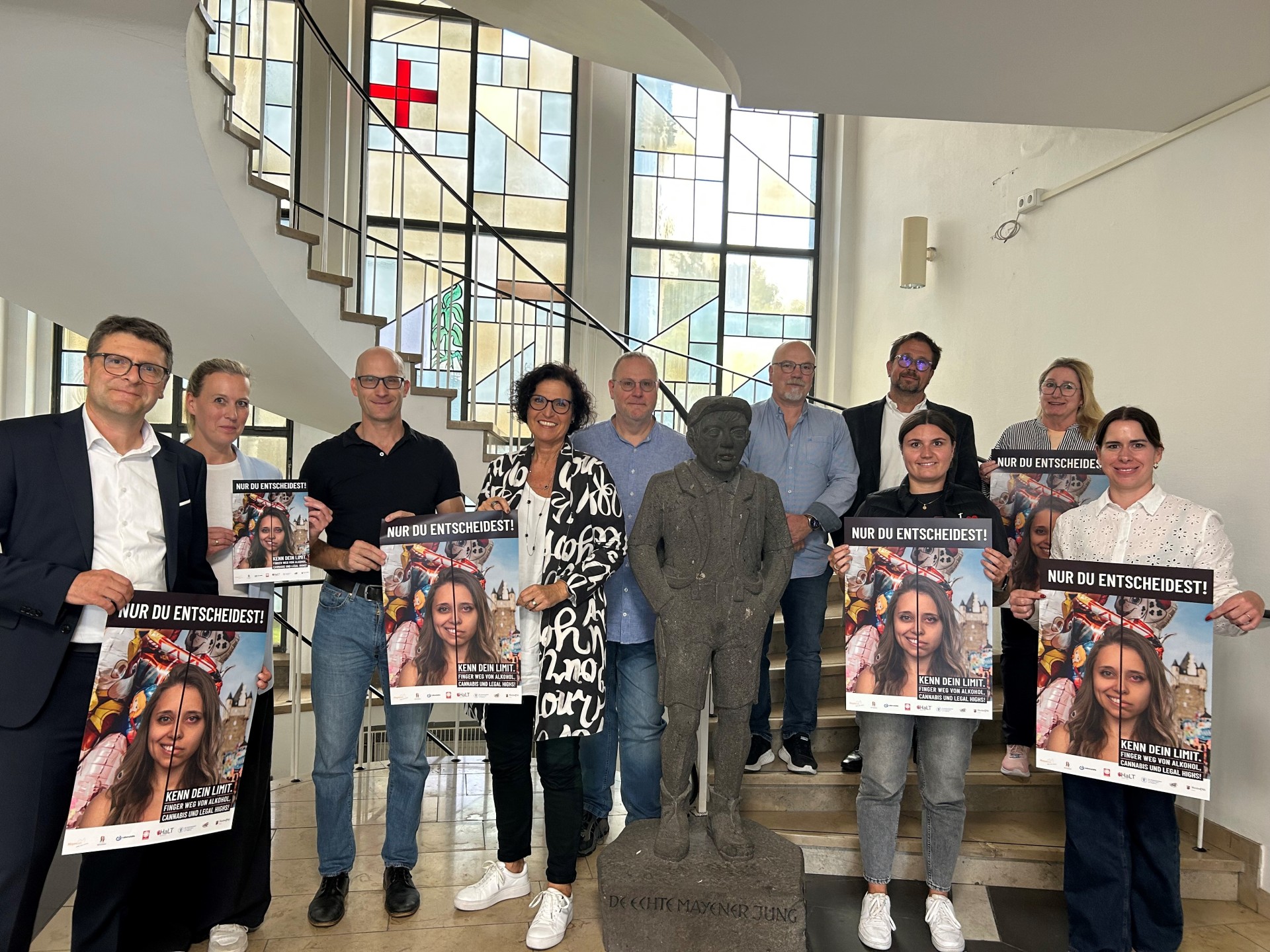 Viele Menschen stehen gemeinsam auf den Treppen des Rathauses und halten das Plakat zum Jugendschutz hoch