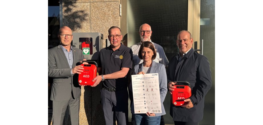 v.l.n.r.: Oberbürgermeister Dirk Meid, Markus Schmitt, Präsident des Rotary Club Mayen 2024/2025, Christina Wolff von der Wirtschaftsförderung, Fachbereichsleiter 1, Uwe Hoffmann und Bernd Faber von Faber Fachgroßhandel (verantwortlich für die Beschaffung der AEDs) bei der Übergabe eines AED vor dem Modehaus Küster
