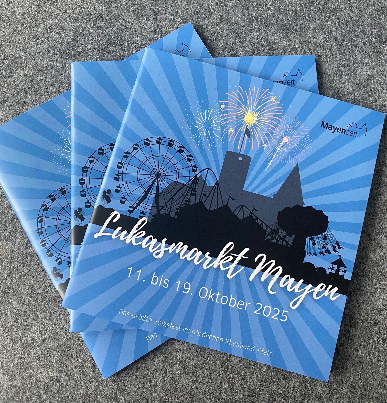 Drei Lukasmarkthefte liegen auf einem Tisch