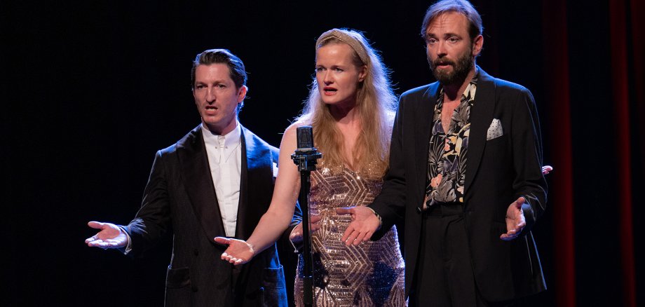 Das A-cappella-Trio „Muttis Kinder“ steht singend auf einer Bühne