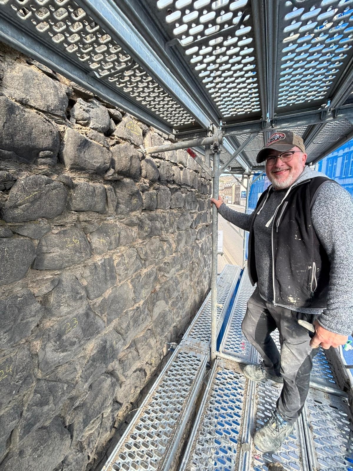 Ein Mann steht auf dem Gerüst an der Stadtmauer