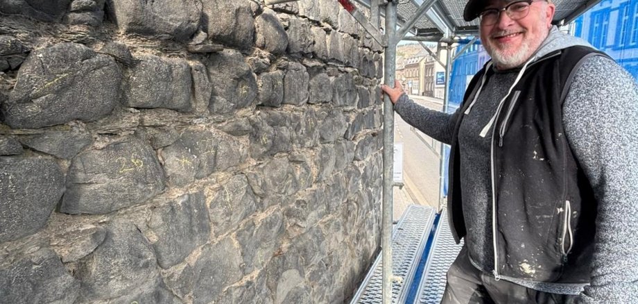 Ein Mann steht auf dem Gerüst an der Stadtmauer