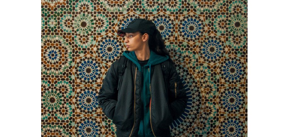 Eine Frau steht vor einer Wand und schaut nach links