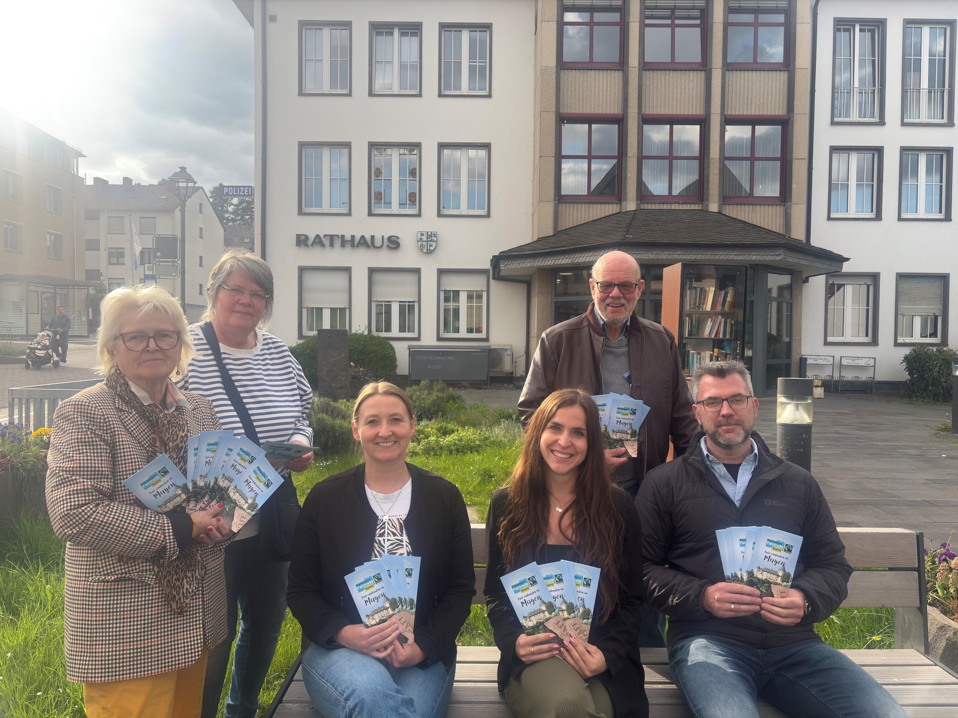 Die Anwesenden der Fairtrade Sitzung mit dem Einkaufsführer vor dem Rathaus