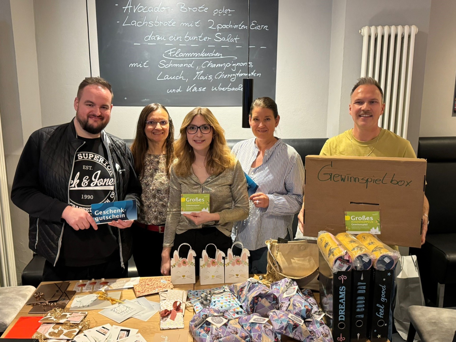 5 Personen stehen vor einem vollen Tisch für ein Foto bereit