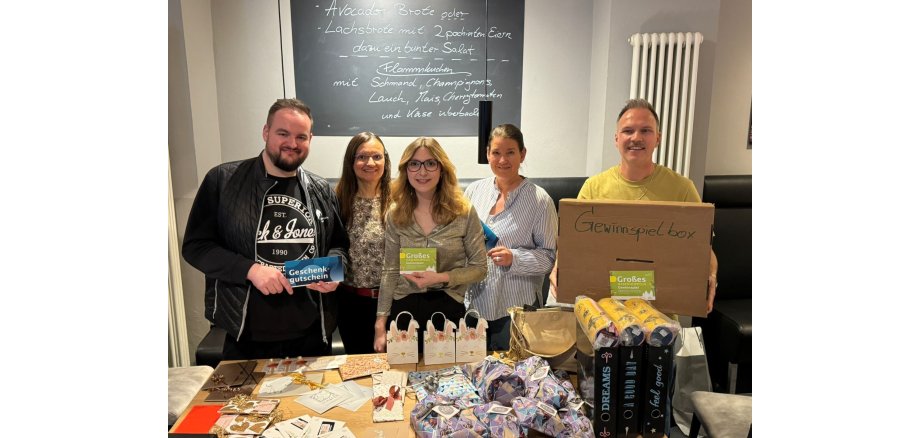 5 Personen stehen vor einem vollen Tisch für ein Foto bereit
