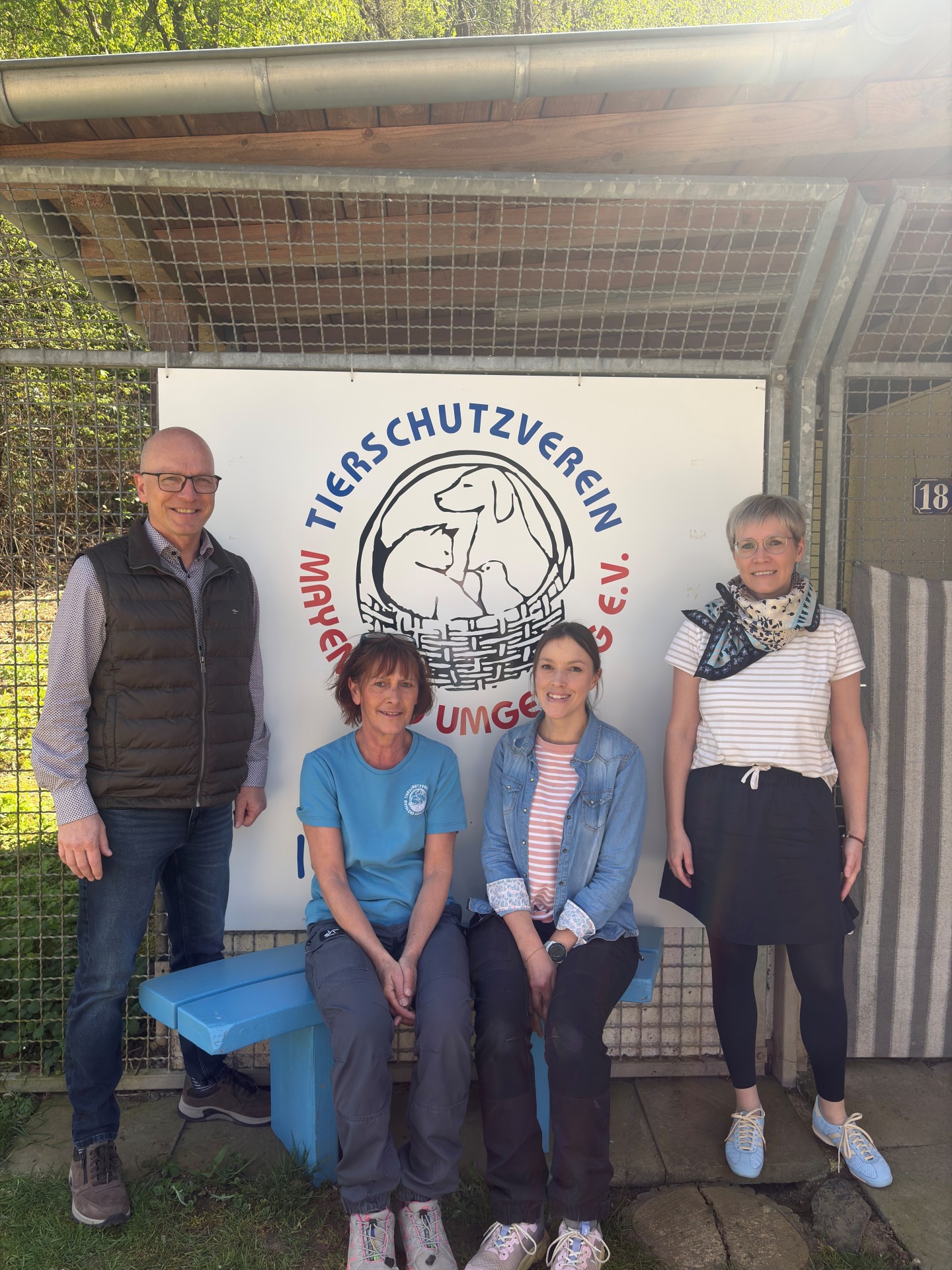 Oberbürgermeister Dirk Meid gemeinsam mit 3 Mitarbeiterinnen des Tierheims vor Logo des Tierheims Mayen