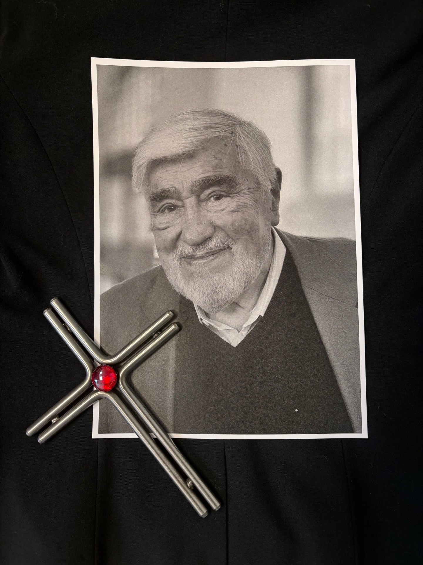 Ein Bild von Mario Adorf liegt gemeinsam mit einem Kreuz auf einem schwarzen Hintergrund
