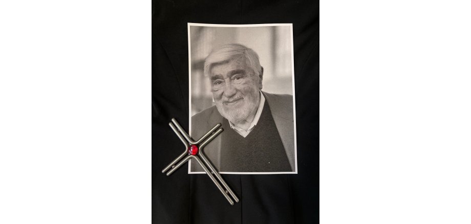 Ein Bild von Mario Adorf liegt gemeinsam mit einem Kreuz auf einem schwarzen Hintergrund