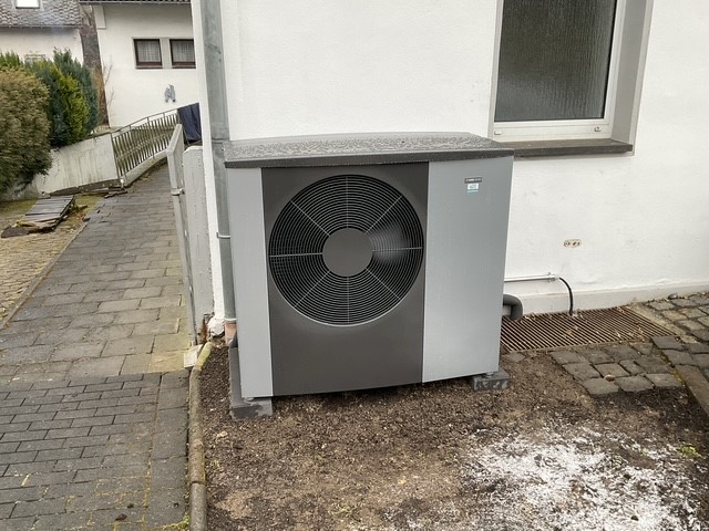 Eine Wärmepumpe steht an einer Hauswand