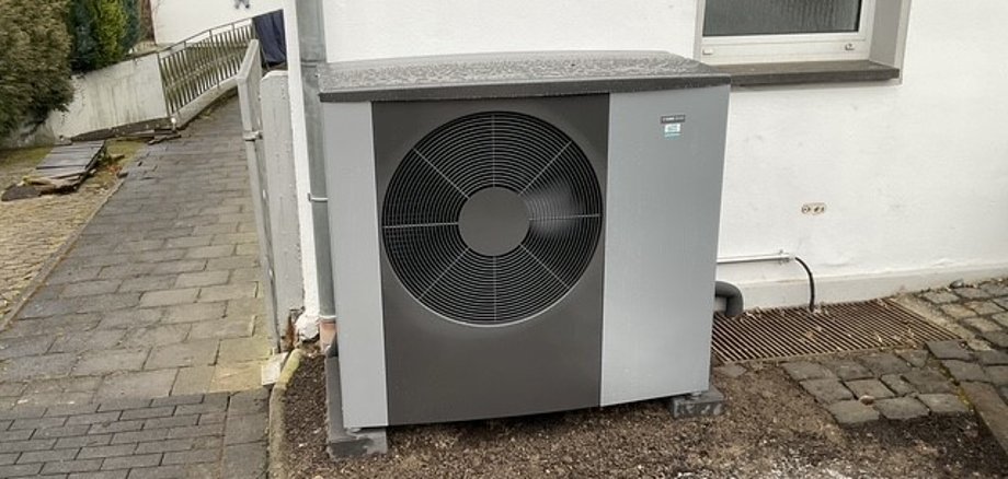 Eine Wärmepumpe steht an einer Hauswand