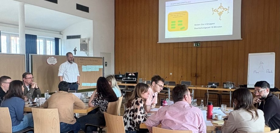 Die Ausbilder sitzen an Gruppentischen und hören den Dozenten zu