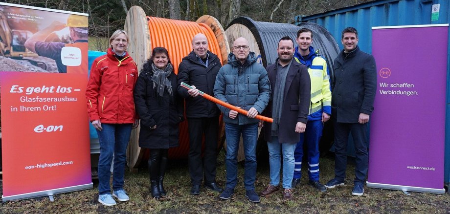Sieben Menschen stehen draußen. Zwei halten symbolisch einen Spaten in der Hand