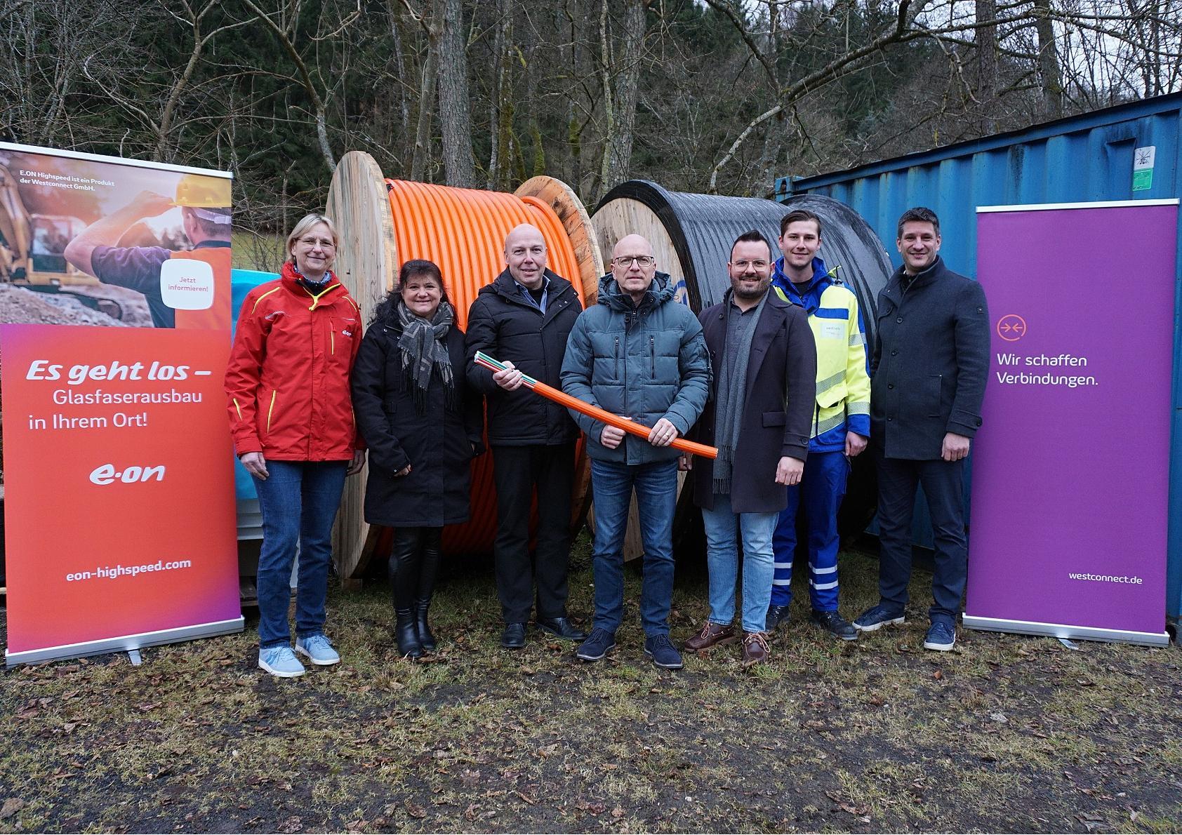 Sieben Menschen stehen draußen. Zwei halten symbolisch einen Spaten in der Hand