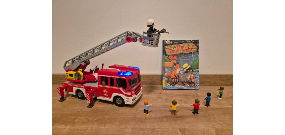 Ein Feuerwehrauto mit einem Buch-Cover und kleinen Personen