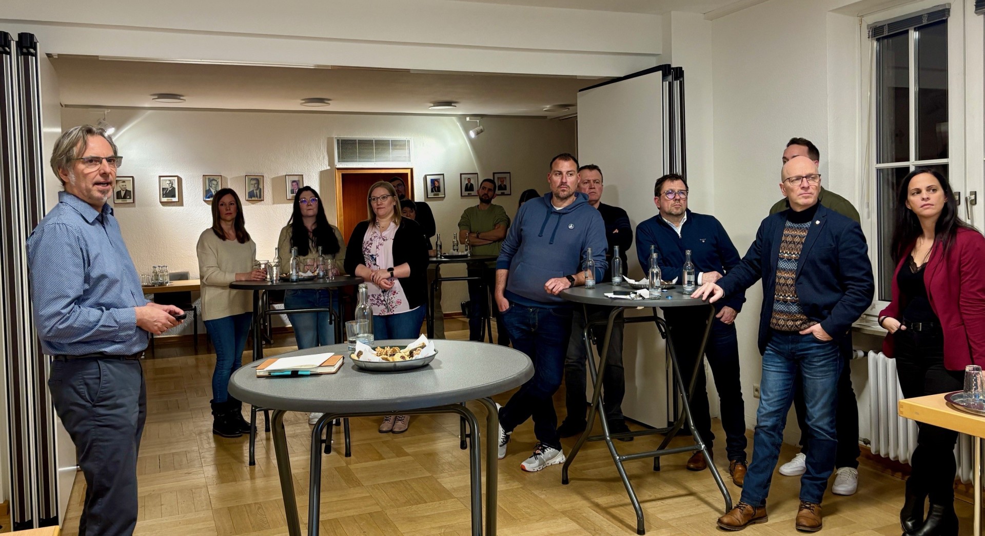 Die Führungskräfte stehen versammelt in einem Raum und hören aufmerksam zu