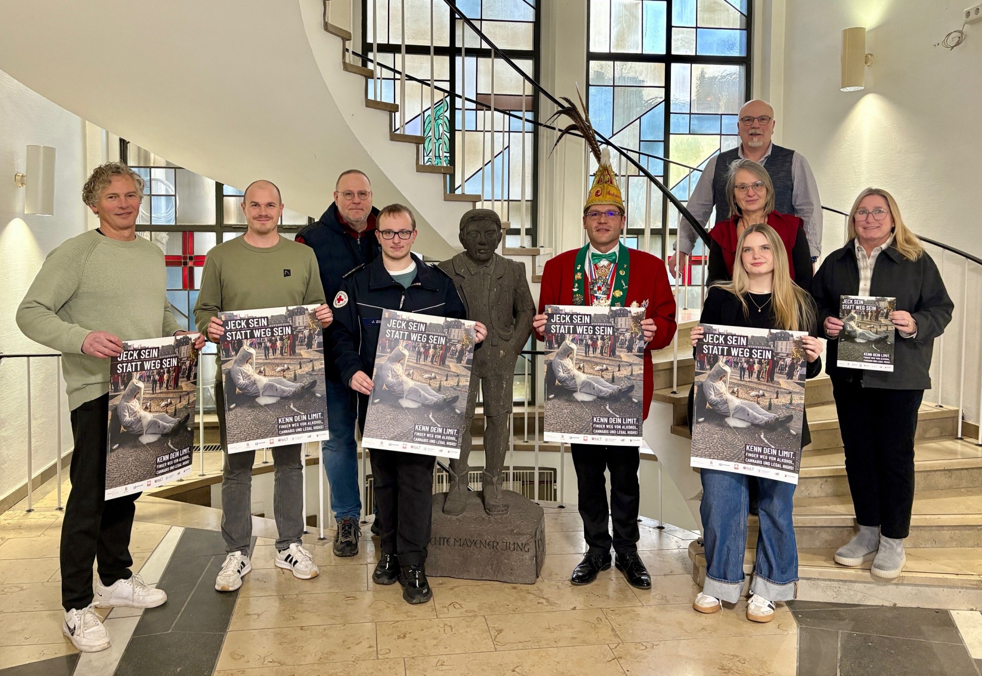 Die Kooperationspartnerinnen und -partner sowie Sponsoren präsentieren stehen im Foyer der Stadtverwaltung und halten das neue Plakat zur diesjährigen Jugendschutzkampagne in den Händen