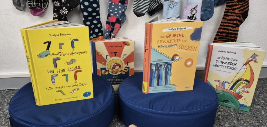 Viele bunte Socken hängen an einer Leine. Davor stehen Kinderbücher