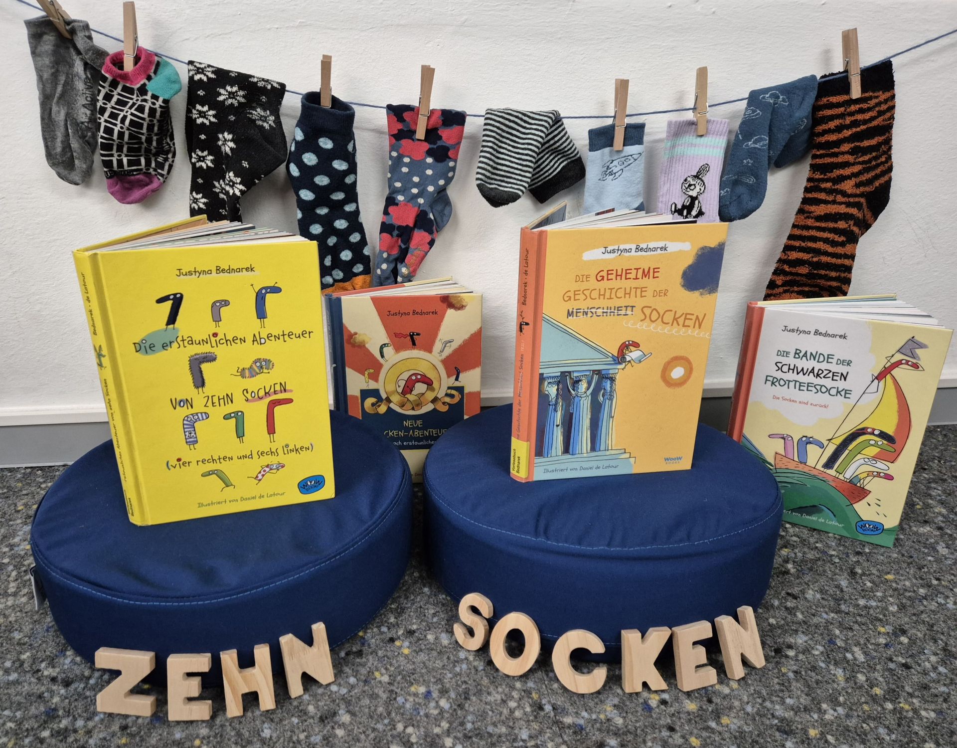 Viele bunte Socken hängen an einer Leine. Davor stehen Kinderbücher