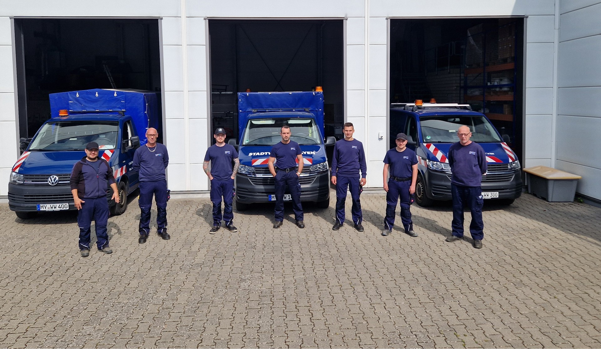 Sieben Mitarbeiter der Stadtwerke Mayen stehen vor den blauen Autos der Stadtwerke