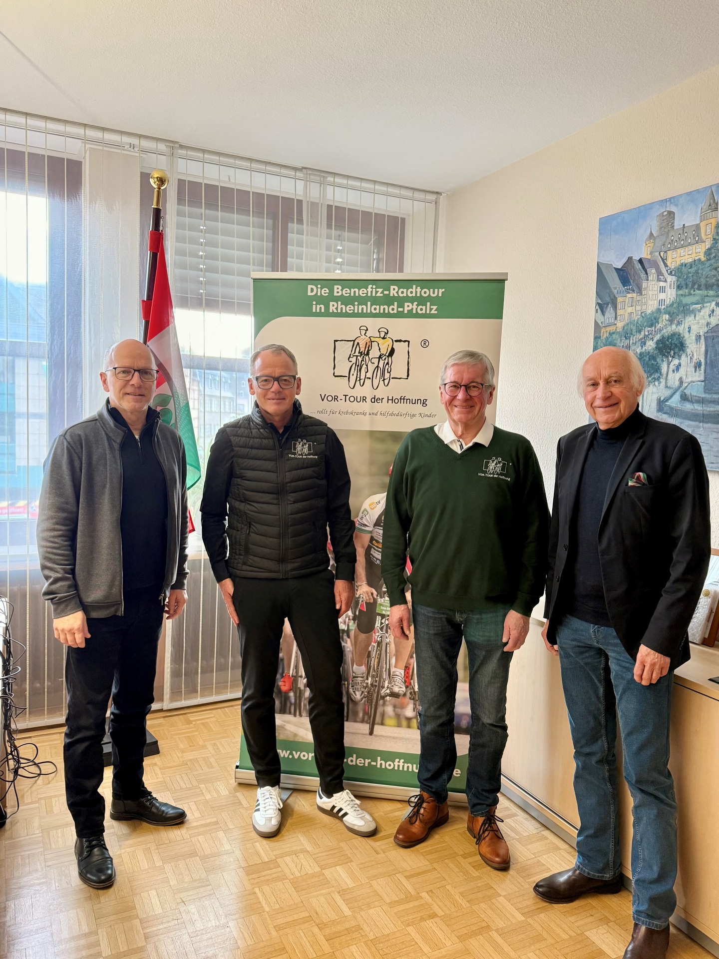 Oberbürgermeister Dirk Meid, Bernhard Sommer, Vorsitzender der VOR-TOUR der Hoffnung, Stellvertreter Hans-Josef Bracht und Bürgermeister Bernhard Mauel stehen nebeneinander vor einem Rollup