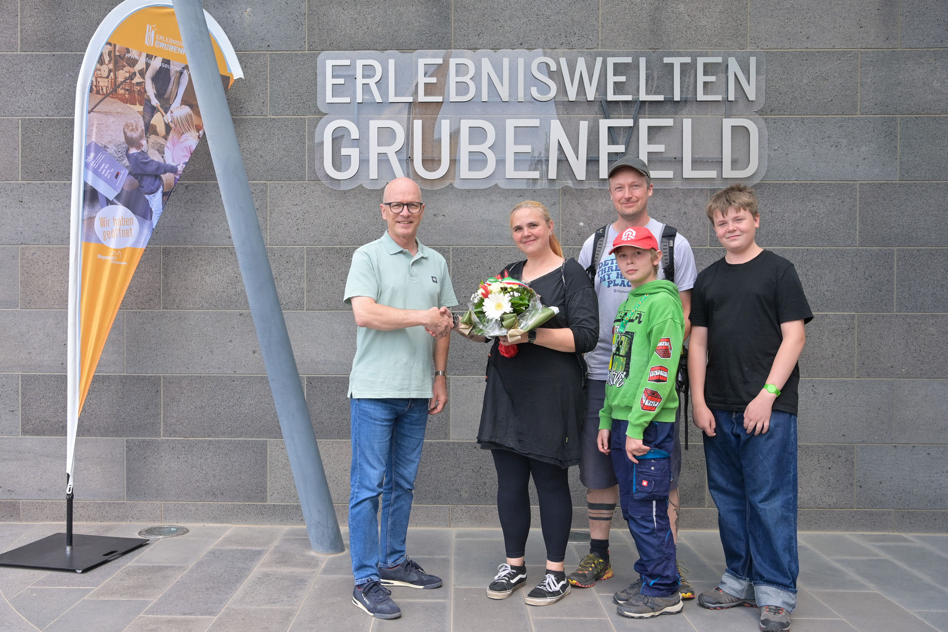 Drei Erwachsene und zwei Kinder stehen vor den Erlebniswelten Grubenfeld