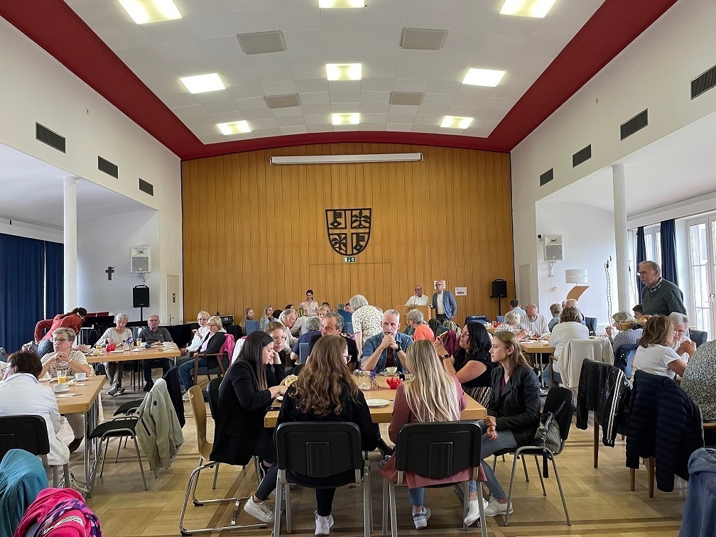 Sitzungssaal der Stadtverwaltung in dem viele Menschen sitzen und frühstücken