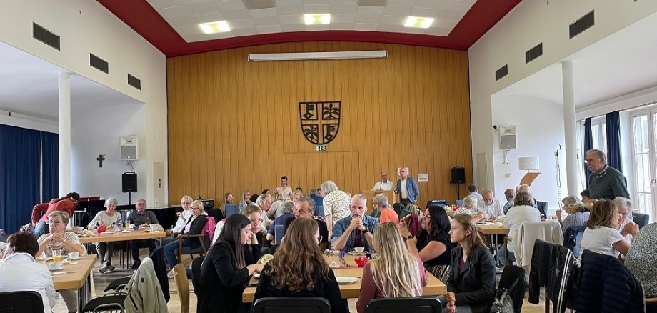 Das Faire Frühstück war auch in den letzten Jahren immer gut besucht Menschen im Sitzungssaal an Gruppentischen am Frühstücken