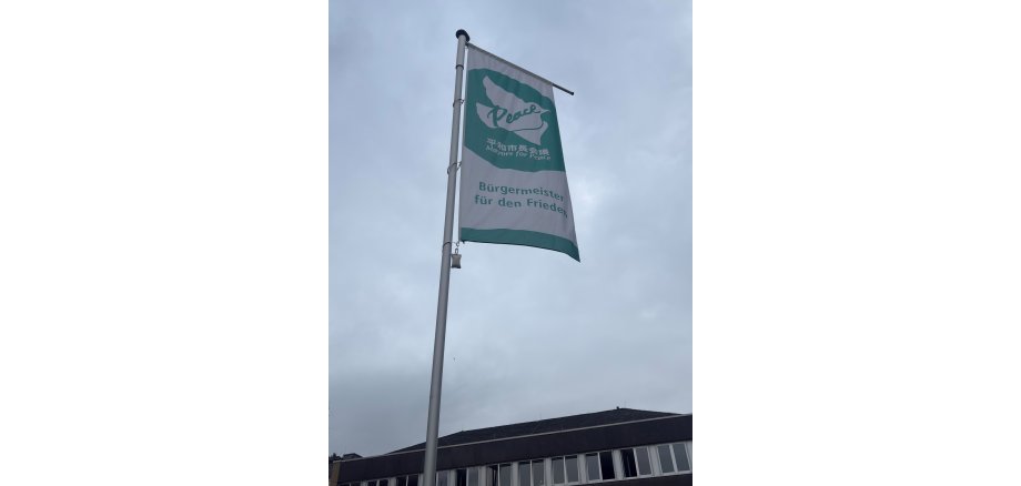 Auch die Stadt Mayen setzte am 8. Juli wieder ein Zeichen gegen Atomwaffen Mayors for Prace Flagge gehisst vor bewölktem Himmel