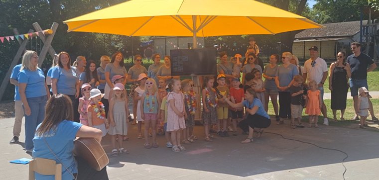 Das Sommerfest der KiTa Weiersbach lud Jung und Alt zum Verweilen ein Viele Kinder und Erwachsene stehen unter einem großen Schirm und führen etwas vor
