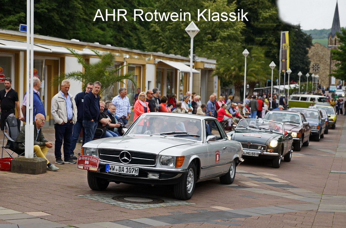 Oldtimer auf einer Straße. Am Rand stehen Zuschauer