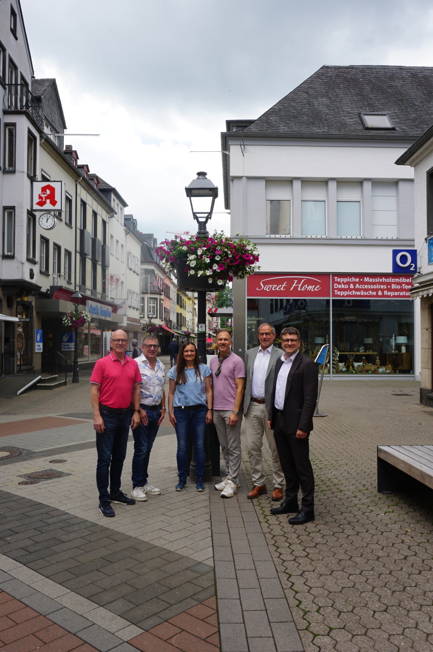 6 Personen stehen vor einer Blumenampel in der Innenstadt