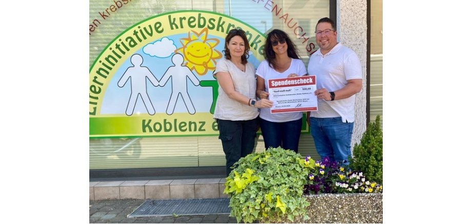 v.l.n.r.: Christiane Müller-Grün, Petra Mähner und Marc Widerstein Zwei Frauen und ein Mann stehen vor einem bunten Schaufenster und halten gemeinsam einen Spendencheck in den Händen