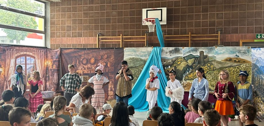 Viele verkleidetet Kinder stehen vor einem bunten Bühnenbild
