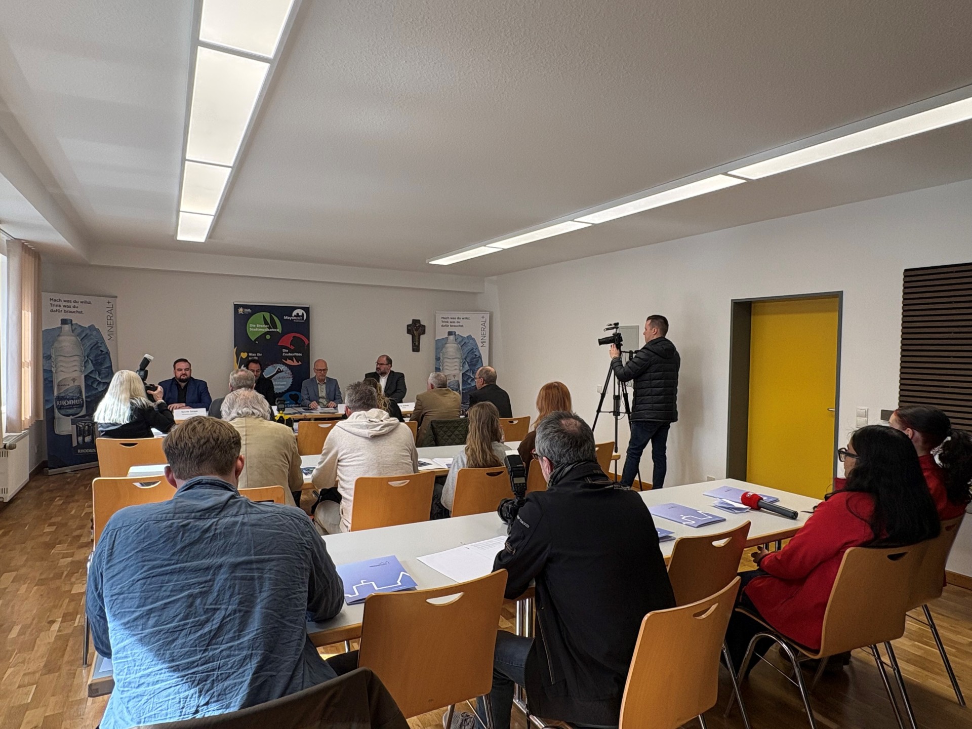 Mehrere Menschen sitzen in einem Raum und hören Sprechern zu