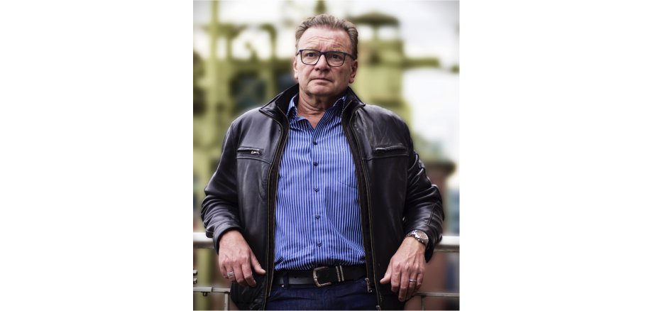 Wolfgang Kaes steht draußen an ein Geländer gelehnt
