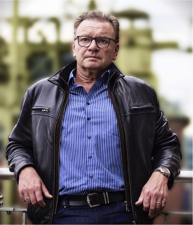 Wolfgang Kaes steht draußen an ein Geländer gelehnt