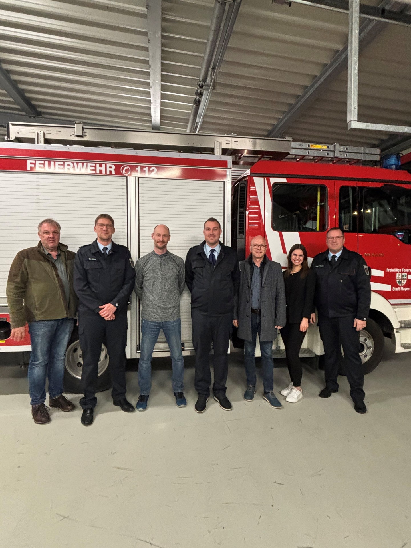 Peter Kaliszan (Wehrführer Löscheinheit Kürrenberg), Stefan Stein (Wehrleiter), Ingo Berg (erneut gewählter stellv. Wehrführer Löscheinheit Kürrenberg), Sascha Reiff (stellv. Wehrleiter), Oberbürgermeister Dirk Meid, Christina Sabel (Bereichsleiterin 4.1), Thomas Velten (stellv. Wehrleiter) stehen nebeneinander vor einem Feuerwehrauto