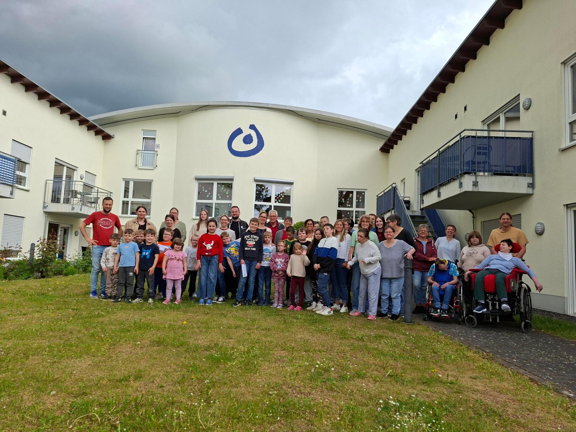 Viele Kinder und ein paar Erwachsene stehen vor der Lebenshilfe