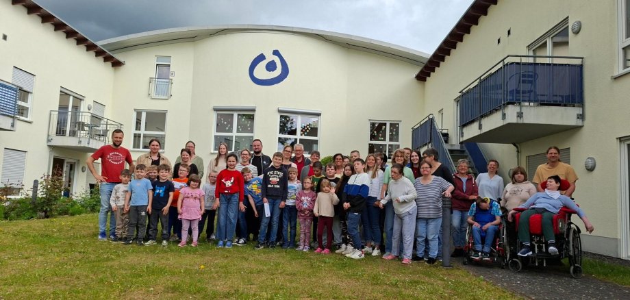 Viele Kinder und ein paar Erwachsene stehen vor der Lebenshilfe