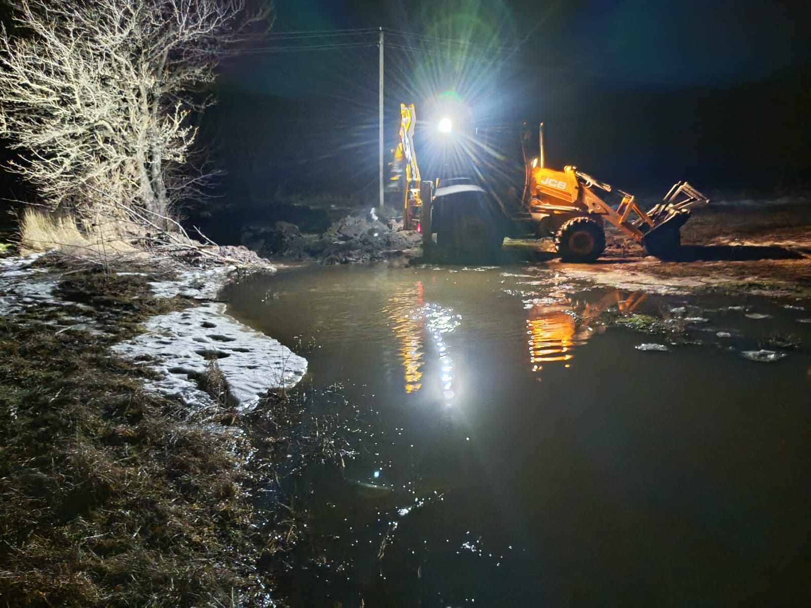 Multifunktionsradlader bei Nacht vor einem kleinem See