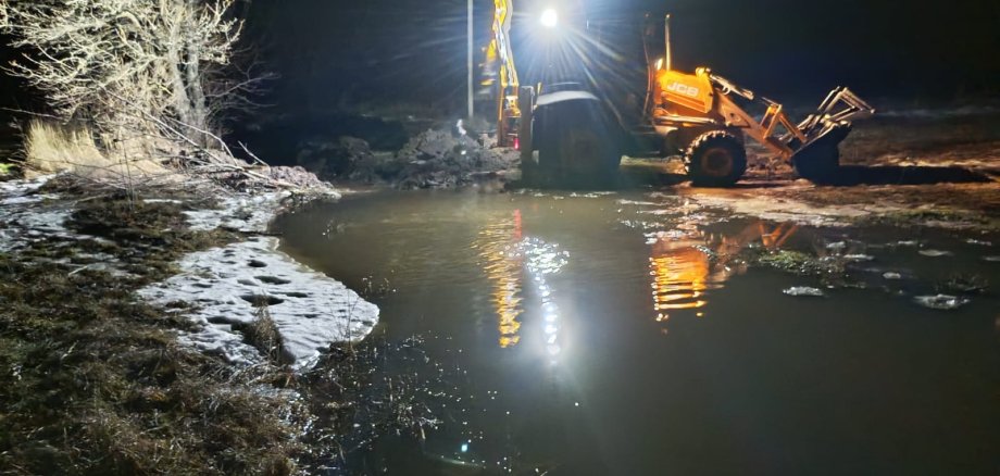 Multifunktionsradlader bei Nacht vor einem kleinem See