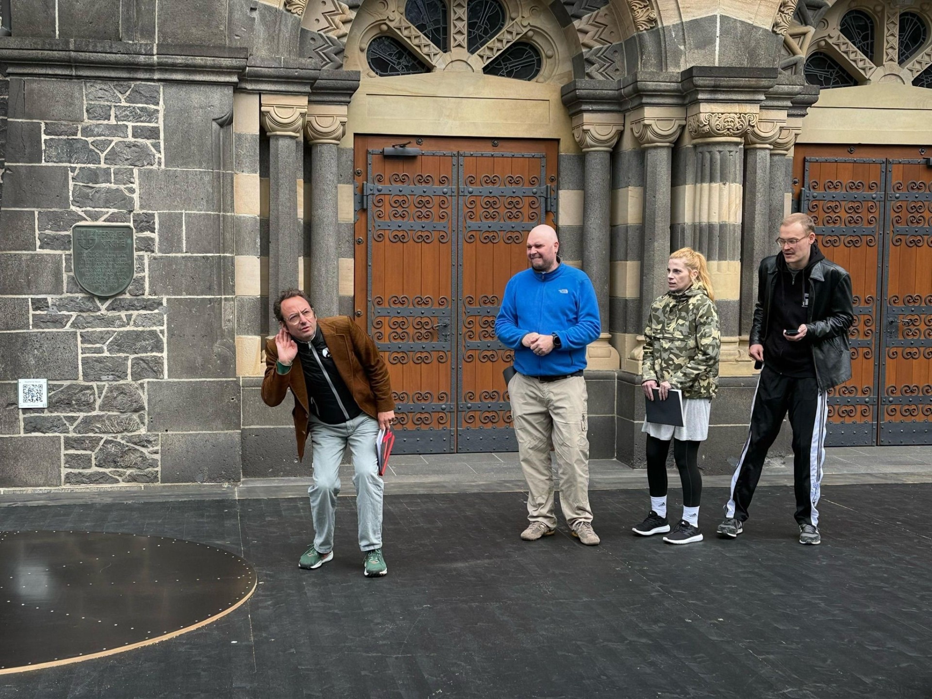 Intendant Alexander May steht mit drei Schauspielern auf der Bühne vor der Herz-Jesu-Kirche