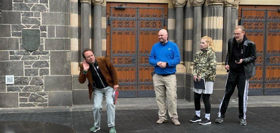 Intendant Alexander May steht mit drei Schauspielern auf der Bühne vor der Herz-Jesu-Kirche