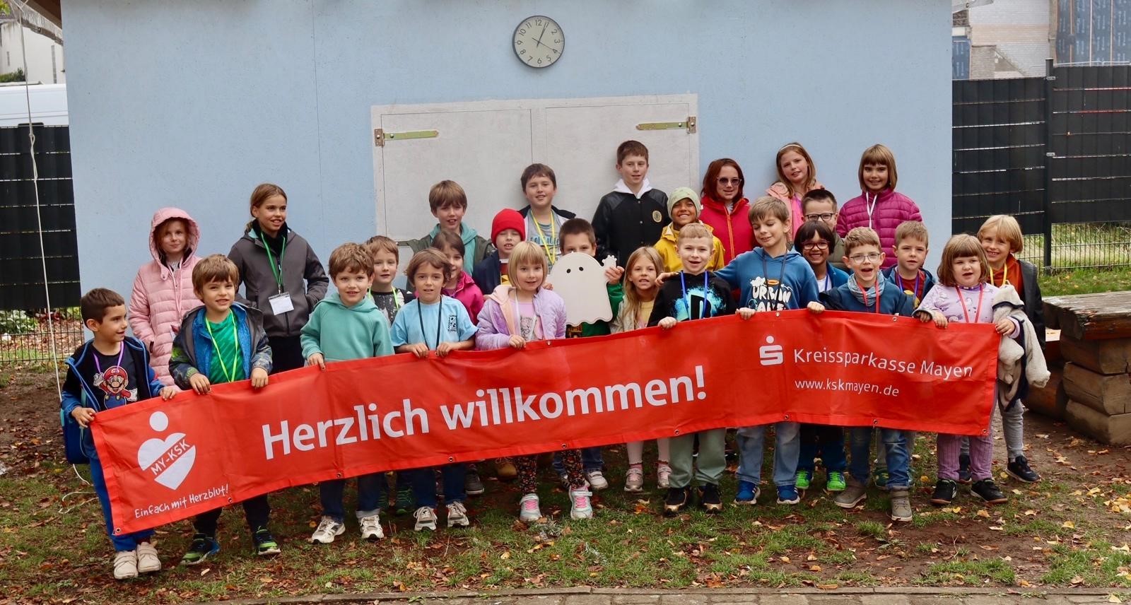 Viele Kinder mit einem Banner vor dem Jugendhaus