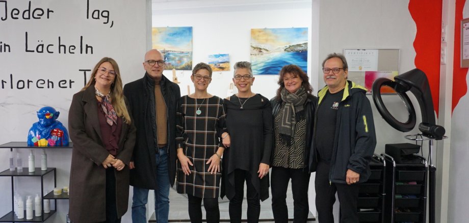 Freude über die Neueröffnung von „VolksSchnitt“ in der Koblener Straße 26. V.l.n.r.: Linda Greger (MY-Gemeinschaft), Oberbürgermeister Dirk Meid, Künstlerin Elisabeth Rechenbach, Inhaberin Manuela Volk-Zawadzki, Dagmar Luxem (Bereichsleitung Wirtschaft und Kultur) und Rolf Schneider (Brückengemeinschaft) Einige Personen im Friseursalon