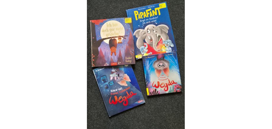 Vier bunte Kinderbücher auf dunklem Hintergrund