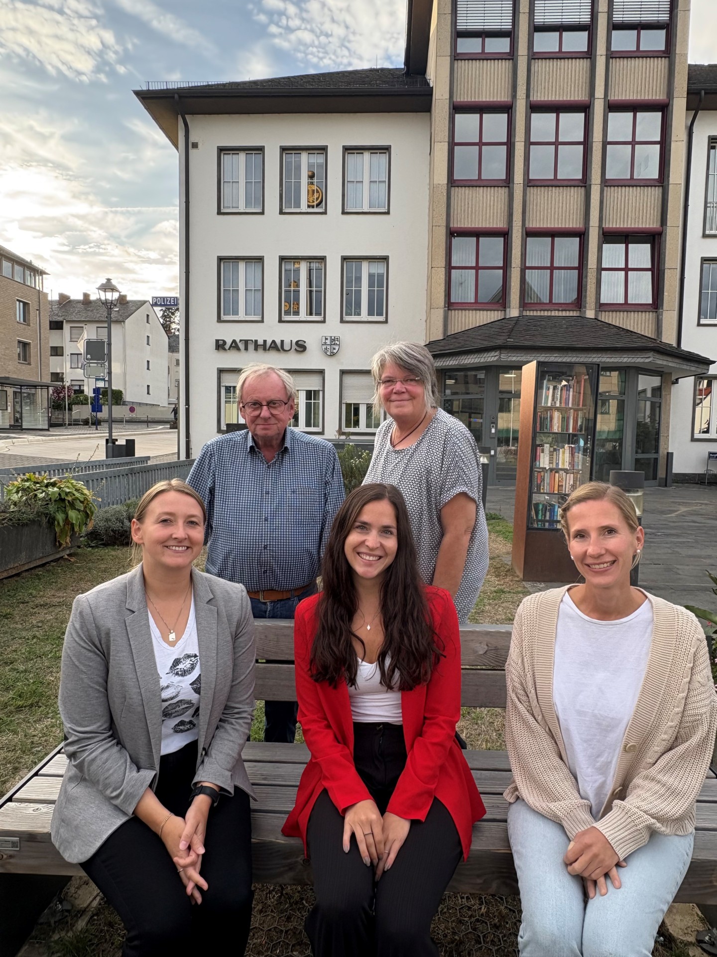 Fünf Menschen sitzen bzw. stehen vor der Stadtverwaltung